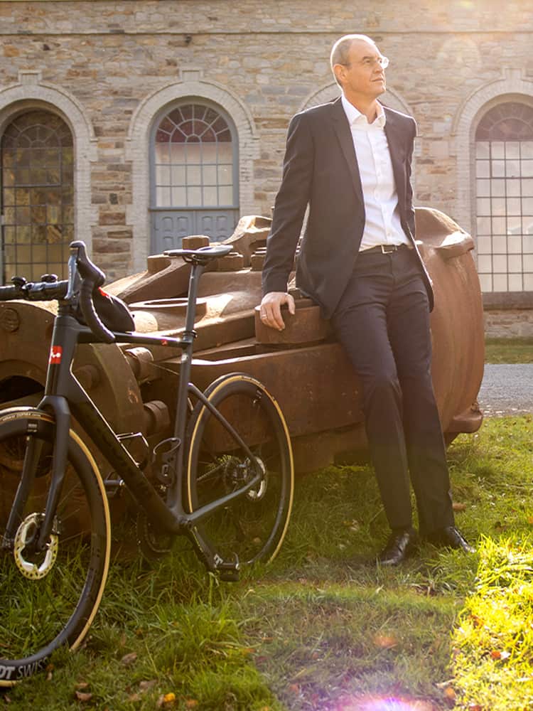 Stefan Baumann lehnt mit Fahrrad an Metallkonstrukt